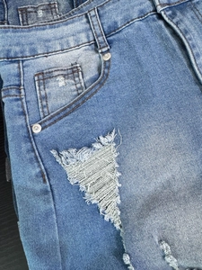 Detalle de pantalones cortos vaqueros azul claro de tiro alto con rotos y remaches metálicos