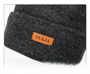 Detail of dark grey knit beanie showing clear texture and orange leather logo patch