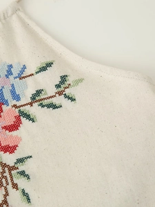 Détail de la broderie florale au point de croix sur tissu en coton et lin beige