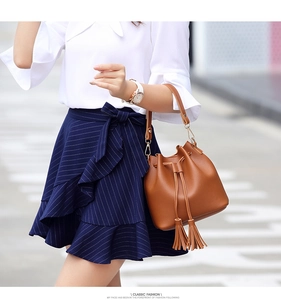 Close-up of brown PU leather bucket bag featuring fringe tassels and drawstring closure