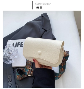 Detail of off-white grain leather crossbody bag with vintage patterned wide strap