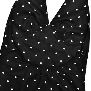 Détail d'une robe licou à pois avec décolleté en V profond, tissu plissé et fermeture éclair
