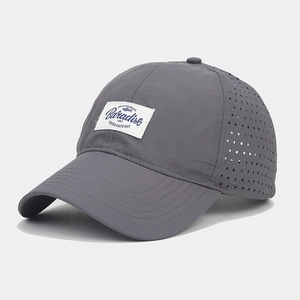 Close-up of laser-cut ventilation holes and woven patch on a gray quick-dry baseball cap