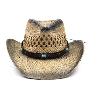 Detail of straw cowboy hat featuring turquoise gemstone leather band and rustic finish