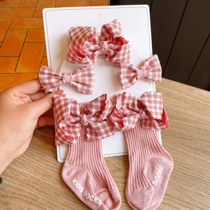 Detail of pink baby socks and red checkered bow headbands set for newborn photography