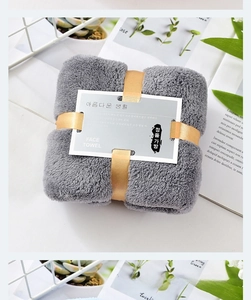 Close-up of gray and light blue coral fleece face towels with golden ribbon gift packaging