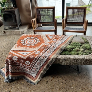 Detail of bohemian woven cotton throw blanket featuring orange geometric patterns and fringes