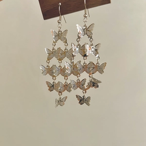 Détails des longues boucles d'oreilles papillon argentées avec design en métal ajouré