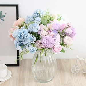 Close-up of blue and pink silk roses in a ribbed glass vase on a wooden table