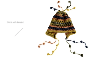 Detail of hand-knitted striped earflap hat with colorful tassels and soft yarn texture
