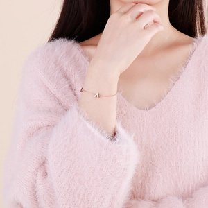 Detailed view of a rose gold 3D V-shaped pendant bracelet on a model's wrist