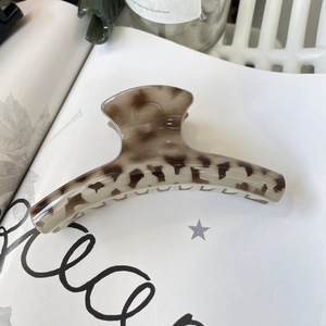 Detailed shot of tortoiseshell hair claw clip with leopard pattern on a white magazine