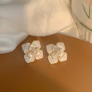 Elegant white camellia flower stud earrings with gold plating on silk background