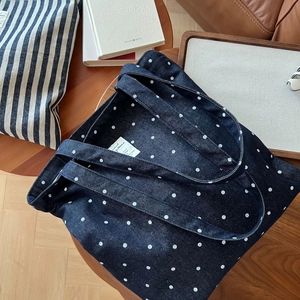 Vue rapprochée du sac cabas en jean à pois bleus montrant la doublure et l'étiquette tissée