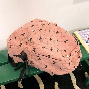 Detail of pink corduroy backpack with diamond stitching and black ribbon bow accents