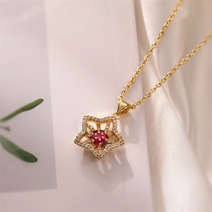 Macro view of gold plated flower pendant featuring red gemstone and zircon accents