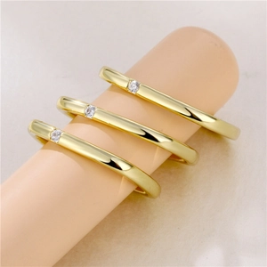 Minimalist gold rings set with sparkling round zircons displayed on a neutral background