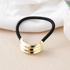 Macro view of elastic hair tie featuring a golden metal knot detail on a neutral fabric