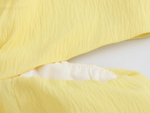 Dettaglio ravvicinato del tessuto plissettato giallo con cuciture e fodera bianca
