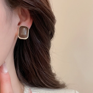 Detail view of retro square stud earrings in amber resin with a gold textured metal frame