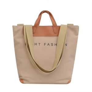 Beige canvas tote bag with brown faux leather handles and detachable webbing strap