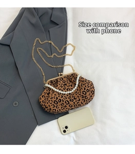 Detailed size comparison of a leopard print shell bag next to a smartphone