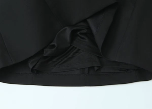 Détail de l'ourlet asymétrique superposé et des coutures de qualité de la robe noire
