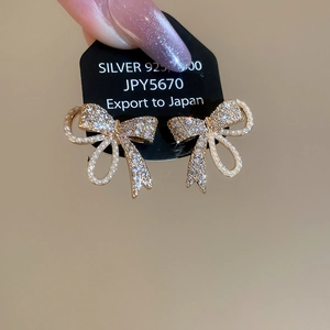 Detailed close-up of S925 silver bow earrings with shimmering zircon and pearls