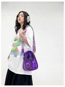 Detail of purple transparent PVC crossbody bag with smiley face and wide woven strap