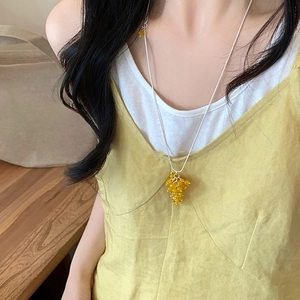Collana minimalista in argento con pendente a grappolo d'uva giallo indossata da modella