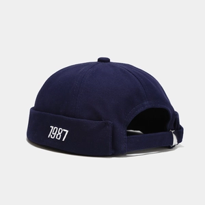 Dettaglio del berretto docker blu navy con ricamo 1987 e fibbia metallica regolabile