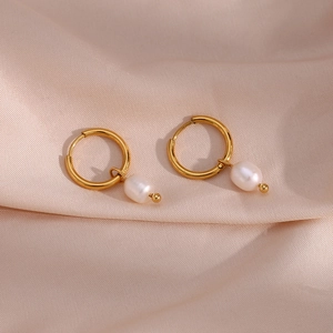 Close-up of gold plated hoop earrings with white freshwater pearls on pink silk fabric