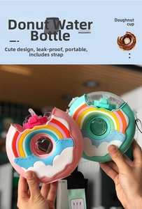 Close-up of a pink doughnut-shaped kids water bottle with a wide adjustable shoulder strap