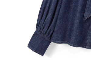 Close-up of deep blue denim shirt cuff with layered ruffles and precise stitching detail