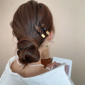Detail of dark tortoiseshell acrylic hair clips with colorful rhinestones on a low bun