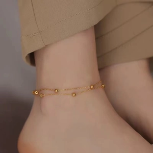 Close-up of double-layer gold bead anklet on ankle with minimalist chic style