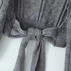 Detail of dark gray cable knit sweater featuring a stylish back bow tie design