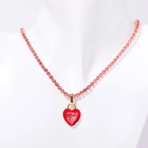 Detailed close-up of a gold tennis chain necklace with a red and pink heart pendant
