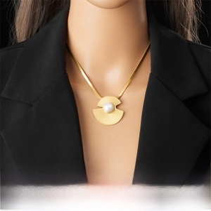 Detail of fan-shaped gold necklace with square pearl on black blazer background