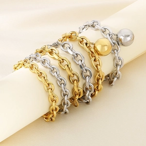 Detailed view of five layered gold and silver chain bracelets with hollow metal ball charms