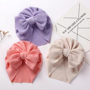 Detailed knit texture of baby turban hats with large bows in purple, pink and beige