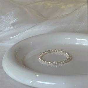 Detailed view of elegant white round pearls bracelet with a sparkling zircon center stone