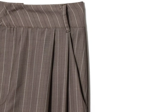 Détail du pantalon rayé marron montrant les coutures professionnelles et le tissu plissé