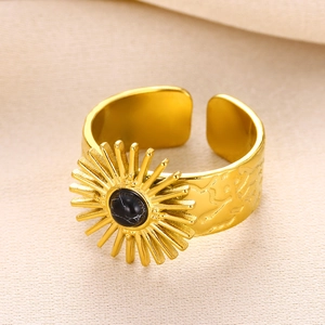 Detail of a vintage gold sunburst ring with an oval black stone on beige fabric