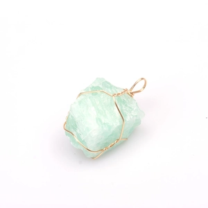Macro detail of natural light green raw stone pendant with golden wire wrap design