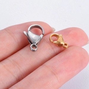Polished stainless steel lobster clasps in gold and silver held by hand for size scale