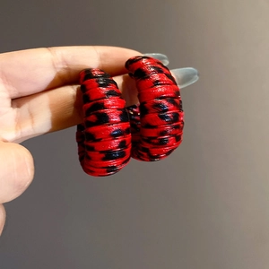 Macro shot of red leopard print C-shape hoop earrings with textured leather wrapping