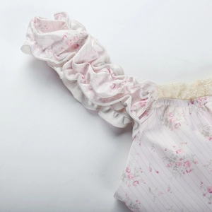 Détail d'un caraco fleuri montrant le motif rose, la texture côtelée et la dentelle