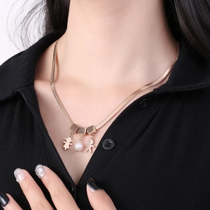 Flat gold snake chain necklace featuring boy girl charms and a white pearl on a model