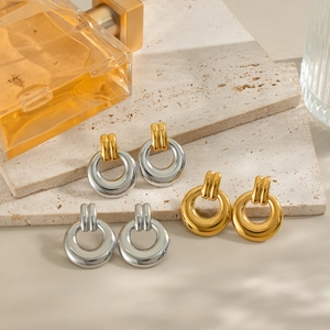 Three pairs of geometric circular earrings in gold, silver, and two-tone finishes on stone
